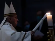 Pope Francis lights a candle at the Easter Vigil Mass in St. Peter's Basilica on April 3, 2021.